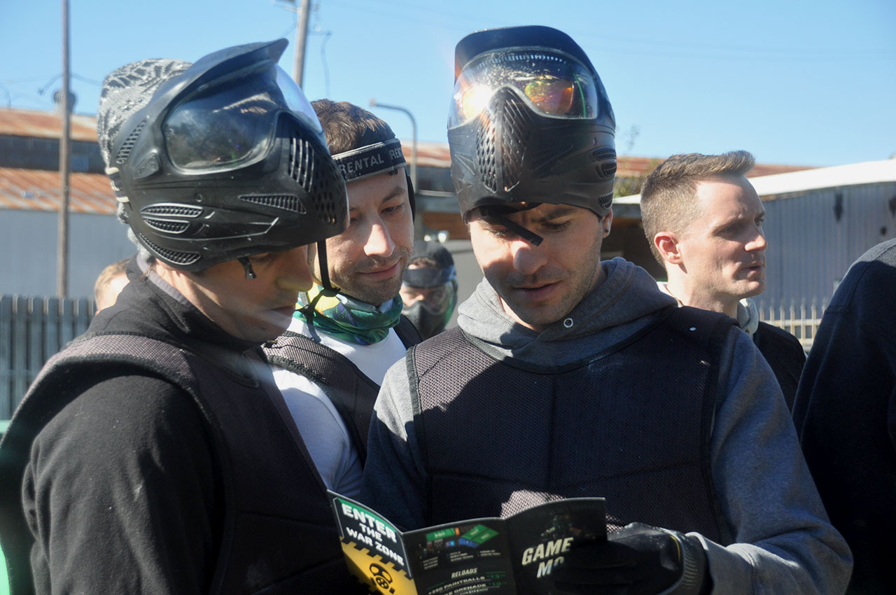 Corporate group in tactical discussion during a paintball team building event
